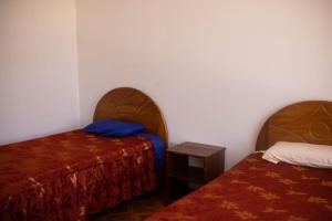 PillcopataHinkiori Inn - Hotel Manu的一间设有两张床和一张小桌子的房间