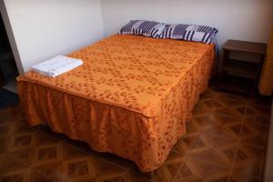 PillcopataHinkiori Inn - Hotel Manu的一张床上的橙色床罩