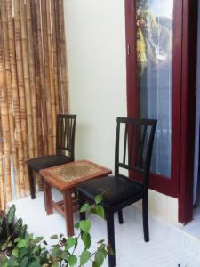 龙目岛库塔Sulis homestay的门廊上的两把椅子和一张桌子