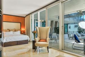 迈阿密海滩Boutique Suites 3 min walk to beach的一间带一张床和一把椅子的卧室以及一个阳台
