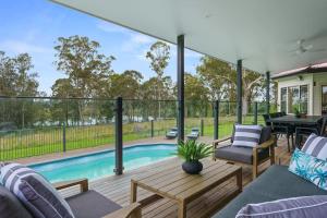 NabiacLake House Family Stay - Pool, Firepit, Games room的一个带桌椅的庭院和一个游泳池