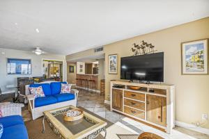 德斯坦Holiday Surf & Racquet 614 Condo的客厅配有蓝色的沙发和平面电视。