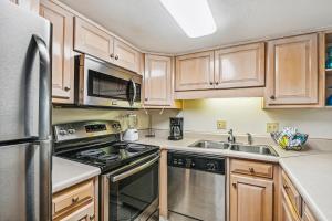 德斯坦Holiday Surf & Racquet 614 Condo的厨房配有木制橱柜和不锈钢冰箱。