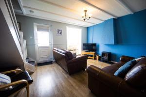 滕比Ploughmans Cottage, St Florence, Tenby的客厅拥有蓝色的墙壁和皮革家具。