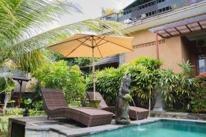 乌布Mancur Guesthouse的游泳池旁的遮阳伞和椅子