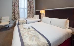 伦敦贝斯特韦斯特伦敦奇司威克宫套房酒店的酒店客房,配有两张床和椅子