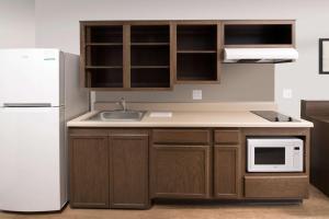 廷利公园WoodSpring Suites Chicago Tinley Park的厨房配有木制橱柜和白色冰箱。