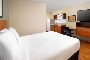 罗密欧维尔WoodSpring Suites Chicago Romeoville的酒店客房设有白色的床和厨房