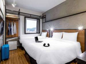 阿鲁雅Ibis Aruja的酒店客房设有一张白色大床和一个窗户。