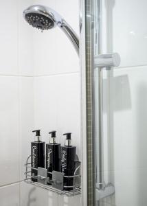 CeresMeldrums Apartments的浴室内有4瓶黑洗发水,放在架子上
