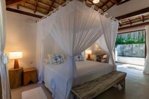 托兰克索DA GRAÇA HOTEL的卧室配有白色天蓬床和木凳