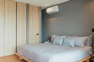 麦德林Wake - branded residences的卧室配有带蓝色枕头的大型白色床