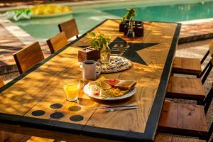 奥尔沃克斯岛Che Holbox Hostel & Bar Adults Only的一张木桌,上面放着一盘食物和饮料
