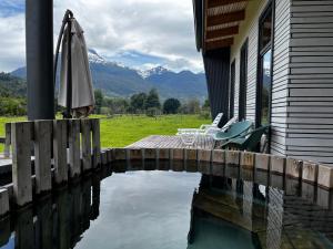 Puerto DunnAysén Lodge - Cabaña con Tinaja的一座带遮阳伞和椅子的房子,以及一座水池