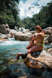 圣拉菲尔La Perla Negra - Black Pearl Eco Hostel的坐在河中岩石上的男人和女人
