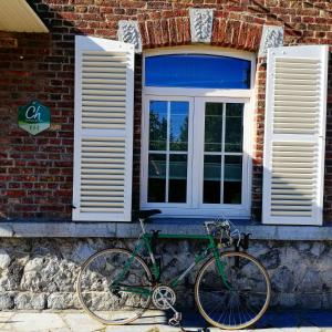 罗什福尔Les2sources Bike-B&B的停在砖房前的绿色自行车