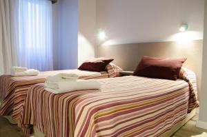 马德普拉塔唯爱苹斯酒店的两张位于酒店客房的床,配有毛巾