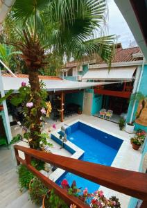 朱奎Tô na Praia Juquehy Pousada的一座带棕榈树和房屋的室外游泳池