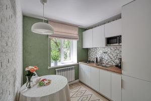 阿拉木图апартаменты Djent-house的厨房配有白色的桌子和窗户。