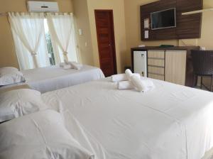 路易斯科雷亚Pousada Bellissima Italia的配有白色床单的酒店客房内的两张床