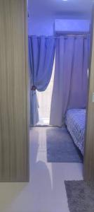 马尼拉Your home in the city的一间卧室配有床和蓝色窗帘的窗户
