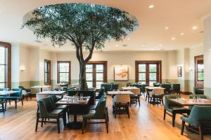 奥斯汀Hotel Viata的一间设有桌椅的餐厅,还有一棵树