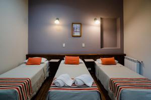圣萨尔瓦多德朱马内圣萨尔瓦多德久久酒店的一间设有三张床的客房,配有橙色枕头
