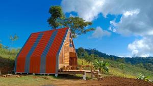 湄宏颂ไร่นิธิสุนทร nithisoonthon farmstay的山丘上一座带五颜六色屋顶的小房子