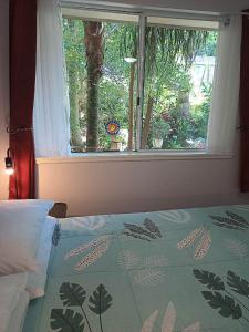 KincumberKincumber Guest Suite的一间卧室设有窗户和一张带鲜花被子的床。