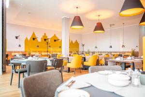 梅彭VIA PLAZA Hotel Meppen的用餐室配有桌子和黄色椅子