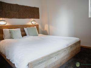 伦德德朗格威尔公寓的一间卧室配有一张带白色床单和枕头的木制床。