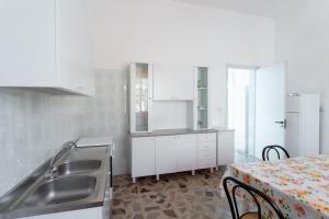 托雷莫泽Appartamento fronte mare e spiaggia的厨房配有白色橱柜、水槽和桌子