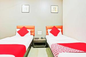 孟买Hotel Amfahh - Andheri West Railway Station的宿舍间内的两张床,配有红色枕头