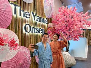 云顶高原The Yanné, Onsen Hotel的两名妇女站在墙上,墙上有雨伞