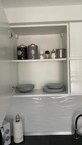 卡尔洛瓦茨M.B.A. APARTMENTS的厨房配有带盘子、锅碗瓢盆的白色架子