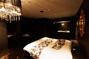旭川旭川ホテルユニオン-大人専用的一间卧室配有一张带白色床单和吊灯的床。