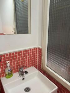 马德里Rooms Moncloa in LOFT - TPH Madrid的浴室设有水槽、镜子和红色瓷砖