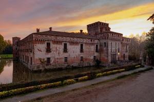 Borgo San GiacomoAgriturismo Padernello的落日时,在水中坐落着一座古老的砖砌建筑