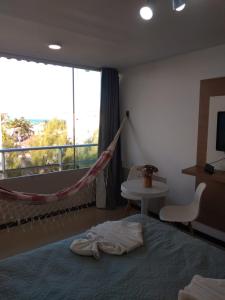 普拉亚多斯卡内罗斯Praia dos Carneiros Flat Hotel Lindo Apto 302的一间带吊床和床的卧室以及一个阳台