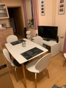 OelsnitzKathrin`s Appartment的厨房里配有白色的桌椅,配有电视