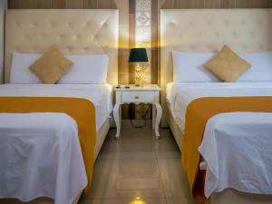 瓜亚基尔Hotel Boutique The Royalty的酒店客房设有两张床和一张带台灯的桌子。