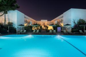 马尔马里E-GEO Easy Living Resort的一座游泳池,在晚上在建筑物前