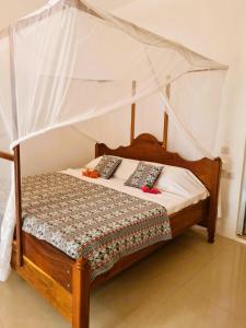 江比阿Ladha ya Zanzibar Boutique Guesthouse的一间卧室配有一张木床和天篷