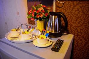 曼谷Visiting Card Hotel & Resort的桌子,桌子上装有杯子,咖啡壶和遥控器