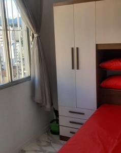 里约热内卢Apartamento encantador com vaga de garagem的卧室配有红色的床和白色橱柜