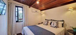 乌巴图巴Casinha D&K - Itaguá的一间卧室设有一张床和一个窗口