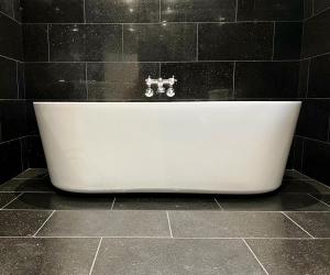 斯卡伯勒花冠馆乡村之屋餐厅酒店的黑色瓷砖浴室内的白色浴缸