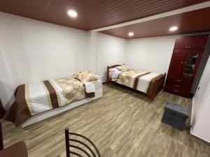 巴尼奥斯Bello apartamento en Baños de Agua Santa的客房设有两张床,铺有木地板。