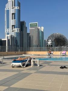 迪拜Travelers Backpackers的躺在游泳池旁躺椅上的男人