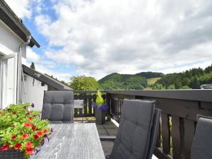 梅德巴赫Detached holiday home in Deifeld with balcony, covered terrace and garden的鲜花阳台的木桌和椅子
